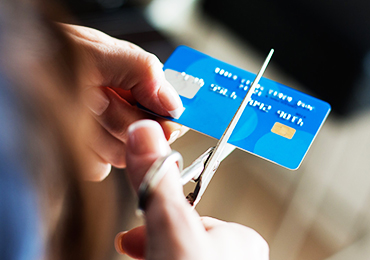 Person cutting a credit card using a scissor
